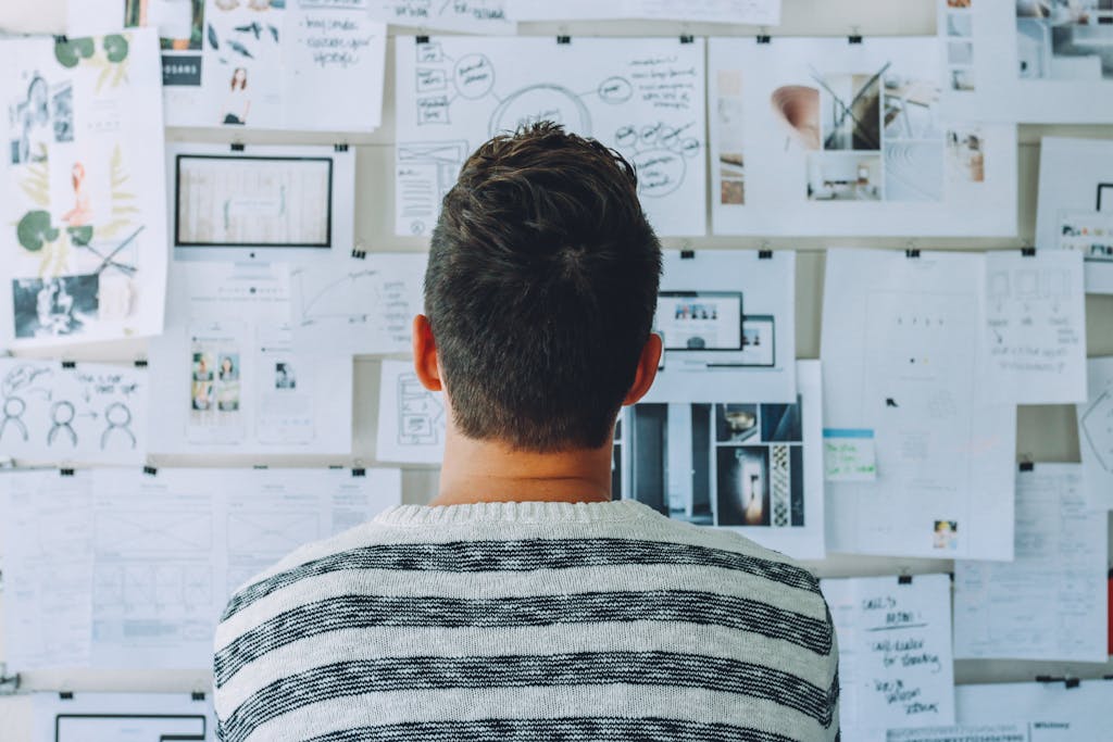 A man stands in front of a wall filled with creative ideas and plans. Ideal for innovation themes.