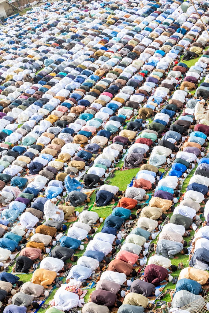 A top view image of a large group of Muslims kneeling in prayer outdoors.